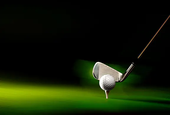 A golf club about to hit the ball from the tee